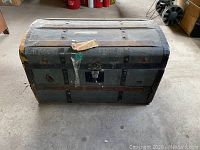 Front view of the antique steel blue steamer trunk showing metal lock and wood slats