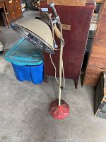 Full view of the vintage Zoalite shop floor light showing the beige metal shade, adjustable arm, cloth-covered electrical cord, and red octagonal base.