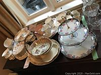 Overall view of tea cups, saucers, dessert plates and three-tier cake stand arranged on table