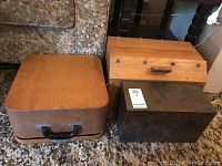 Photo of vintage Remington typewriter case and two wooden boxes sitting on carpeted floor.
