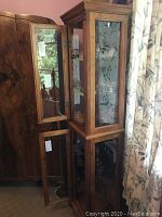 Full view of wood and glass display cabinet with two open front doors showing interior shelving and lighting.