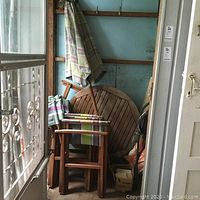 Round tabletop leaning against wall with folded chairs stacked in front