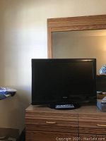 Photo of a 37-inch Toshiba flat screen TV placed on a wooden TV stand with a remote control in front of it.