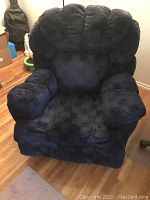 Front view of a large black corduroy recliner chair with thick cushioned seat, armrests, and backrest.