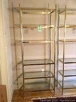 Full view of tall chrome etagere with five glass shelves in a room corner, showing overall size and form.