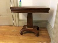 View of the game table in the closed position, showing compact folded wooden top and pedestal base