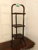 Full view of the triple serving stand with three folded wooden shelves and tripod base.