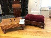 Pair of footstools, one red velvet upholstered and one carved wood, with wooden floor background