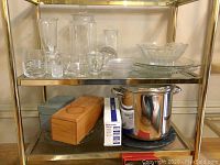 Shelving unit with glass apothecary jars, bowls, metal stove pot, mandoline slicer in box and wooden box.