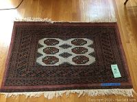 Full view of the oriental area rug on a hardwood floor, showing details of pattern and fringes.