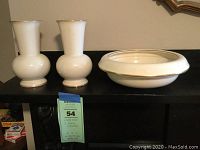 Pair of white Lenox vases and small lamp reflector placed on a black surface.