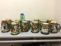 Twelve Royal Doulton Dickens Christmas ceramic mugs displayed in a row showing side profiles and details of relief scenes and brown bases and handles.