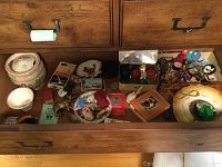 Wide drawer view showing ceramic jar, animal figurines, tins with trinkets, decorative items, and small tops