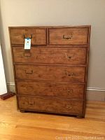 Full front view of oak six-drawer chest with brass hardware and lot tag attached