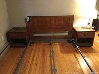 Full view of queen headboard mounted on metal frame rails flanked by two matching nightstands