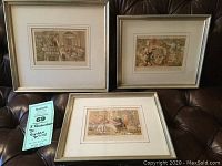 Shows the full set of three framed prints placed on a leather chair, clearly showing the framing and matting style