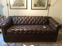 Front view showing full sofa silhouette, tufted upholstery, rolled arms and nailhead trim.