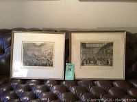 Two framed antique English prints titled 'Society for the Encouragement of Arts' and 'Christie's Auction Room' resting against a couch.