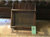 Front view of scoop showing wooden frame, metal tines and wire mesh