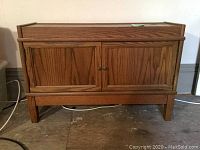 Front view of wooden small stand showing two cabinet doors and simple wooden knobs.