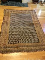 Full view of rectangular oriental rug laid on wood floor showing overall color and pattern