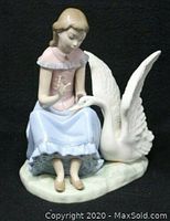 Front view of the NAO by LLADRO "My Swan" figurine showing the girl in pink blouse and blue skirt sitting beside a white swan.