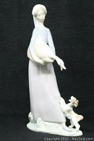 Front view of Lladro porcelain figurine showing girl holding a goose with a dog at her side.
