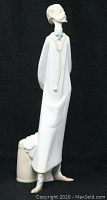Full side view of Lladro doctor figurine with stethoscope and long coat, shoes in beige, and object behind the figure.