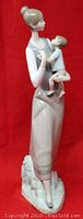Front view of LLADRO porcelain figurine "Motherhood" depicting a woman holding a child, standing on a textured base.