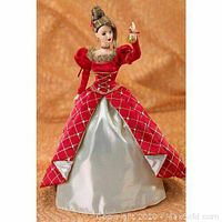 Full view of the Barbie doll outside the box, showing the detailed red and silver gown and styled hair with holiday accessory in hand.