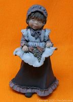 Front view of Elisa Acisclo figurine showing girl in bonnet and dress holding flowers.