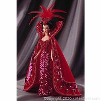 Full view of the Barbie doll wearing the red sequin gown, feathered heart headdress, and heart-embroidered cape.