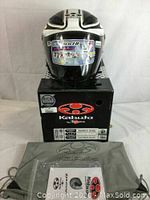 Front view of helmet on top of original Kabuto box with grey carrying bag visible.