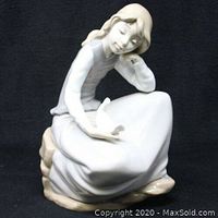 Front and left side view of the NAO LLADRO porcelain figurine of a girl holding a dove seated on a rock base, showing detailed posture and expression.