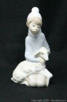 Front view of the Lladró porcelain figurine depicting a boy shepherd kneeling and holding a lamb, showing clear details of the figure's face and lamb's texture.