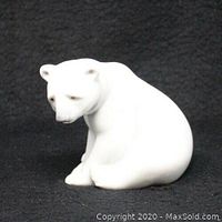 Front angle view of white seated polar bear figurine showing facial features and sitting posture.