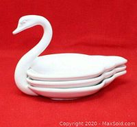 Stacked white porcelain swan plates showing main swan dish with raised neck and two smaller plates stacked inside.