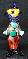 Front view of colorful Murano glass clown figurine, showcasing red polka-dot body, green buttons, yellow hair, and black top hat.