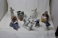 Overview of all figurines including nurse playing violin, cats, elderly woman, abstract dancers, and seated woman reading or sewing