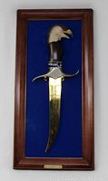 Full view of the framed gold-tone eagle handle knife against blue felt background