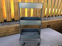 Front view of the 3-tier metal cart showing rectangular trays and overall frame structure with handle.