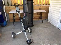 Image showing collapsible 2-wheel push golf cart with metal frame and wheels.