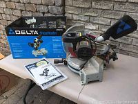 Overview of saw on table with original box and instruction manual in view