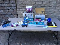 Overview of assorted pot light boxes and multiple boxed and loose bulbs on beige table against brick wall