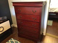 Front view of the tall wood dresser showing 6 drawers with metal handles and cherry stain finish.