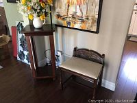 Vanity bench and pedestal table together against wall with painting above