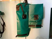 Two green SealLine drybags hanging on a hanger with roll-top closures secured by black straps and buckles.
