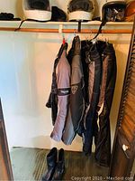 Three helmets on top shelf and hanging Triumph jackets and pants