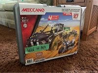 Front view of the Meccano building kit metal case showing branding, model details, age recommendation, and piece count.