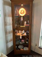 Full front view showing cabinet with glass door, interior shelves, and built-in light